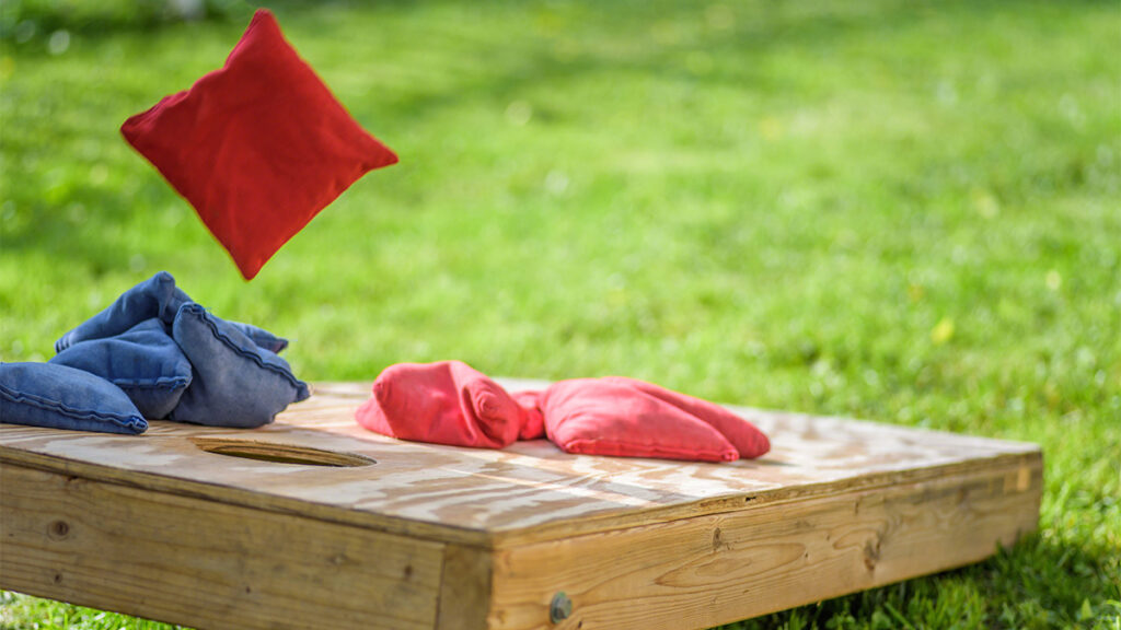 Cornhole board with red and blue bean bags positioned on top