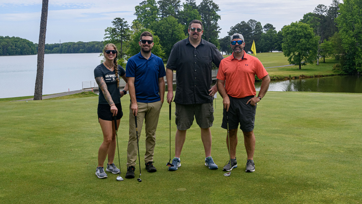 4team members posing for a photo during the jack cooke golf classic.