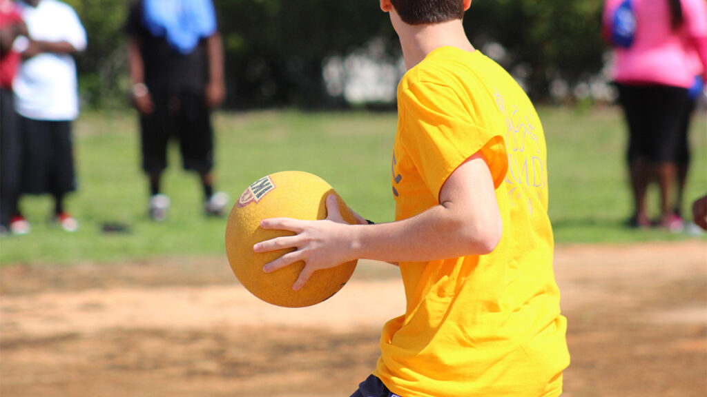 Kickball player holding yellow ball getting ready to pitch.